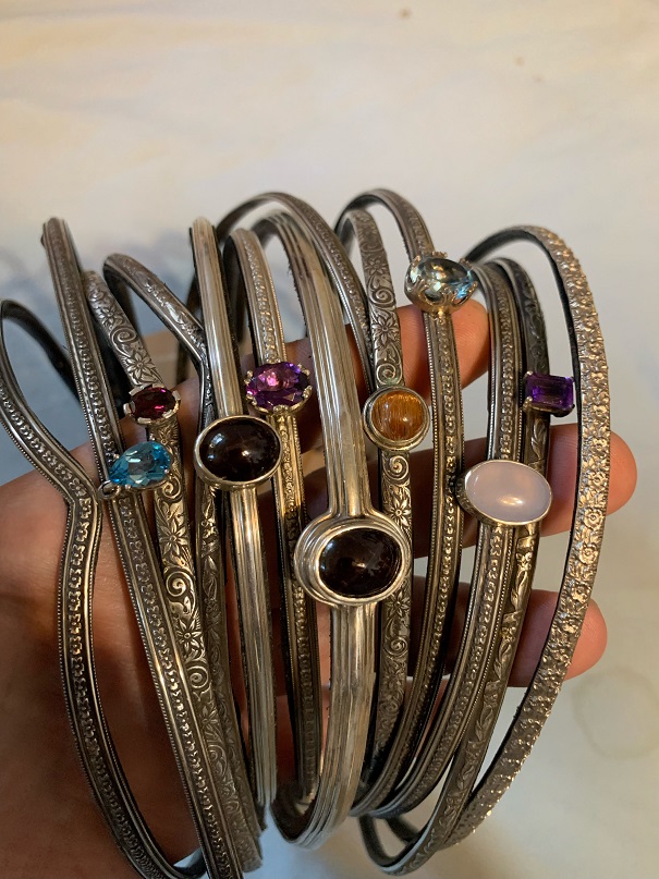 A handful of engraved sterling silver circlets set with colorful gemstones.