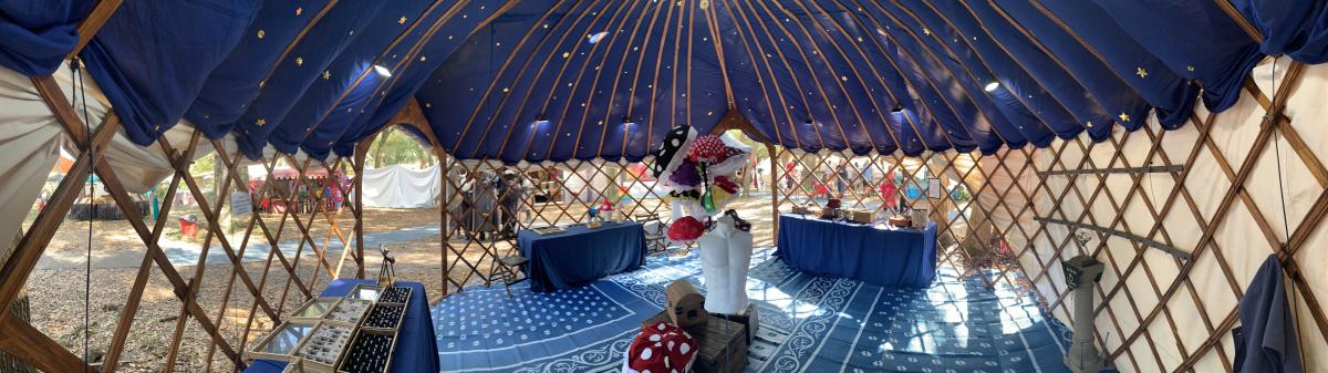 Panorama of the yurt interior: navy starry ceiling, wooden lattice, jewelry cases, and mushroom hats.