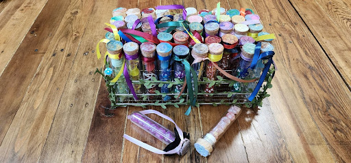 Corked glass vials of polyhedral dice, tied with ribbons, packed in a vine wrapped basket.