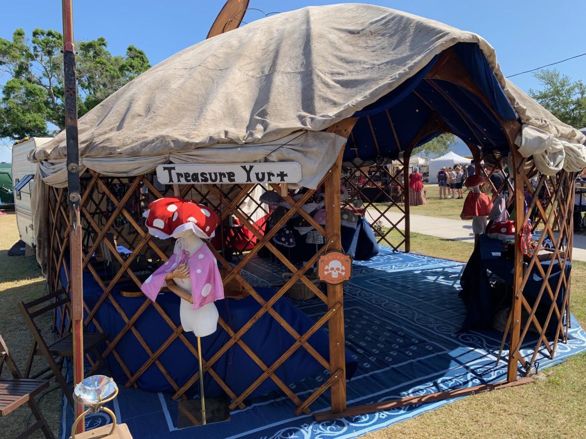 Yurt entrance with a wooden Treasure Yurt sign, an orange Enter If You Dare skull sign, and a mushroom hat mannequin.