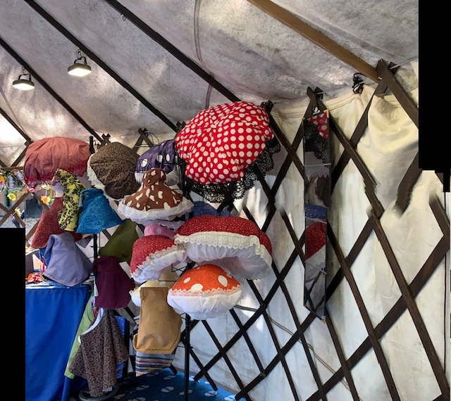 A wall of handmade mushroom hats and crowns inside the yurt.
