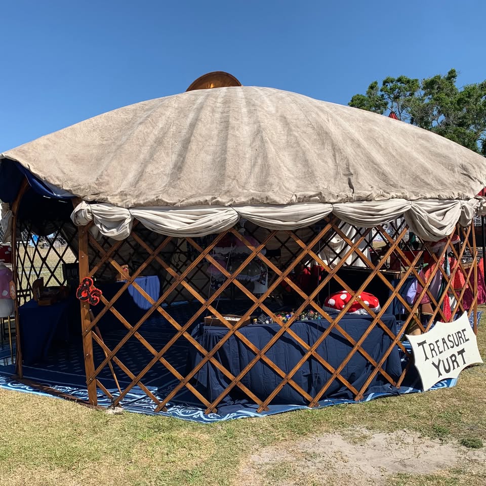 The tan canvas Treasure Yurt on the faire grounds, wooden lattice walls, blue mats, and a shield-shaped Treasure Yurt sign.