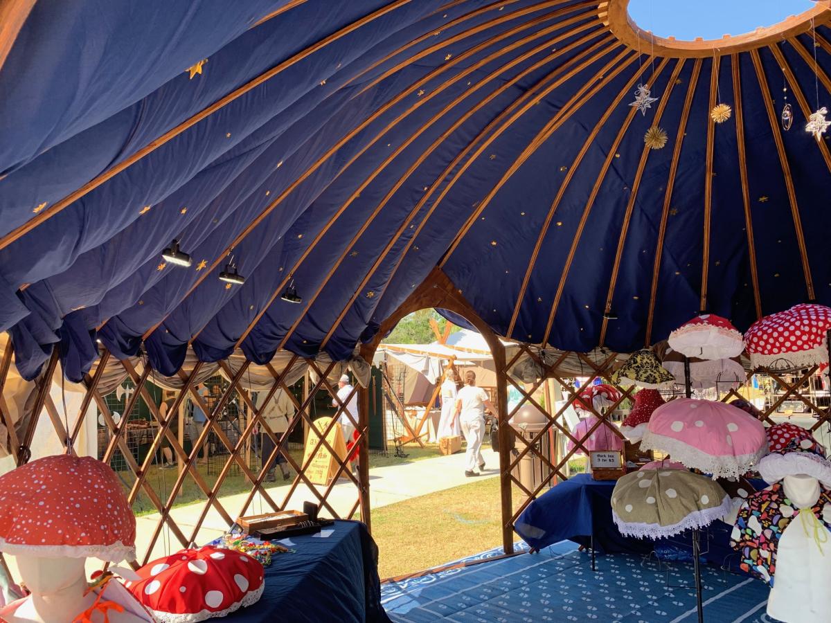 Looking up inside the yurt at the royal-blue starry ceiling, lattice walls, and a display of mushroom hats.