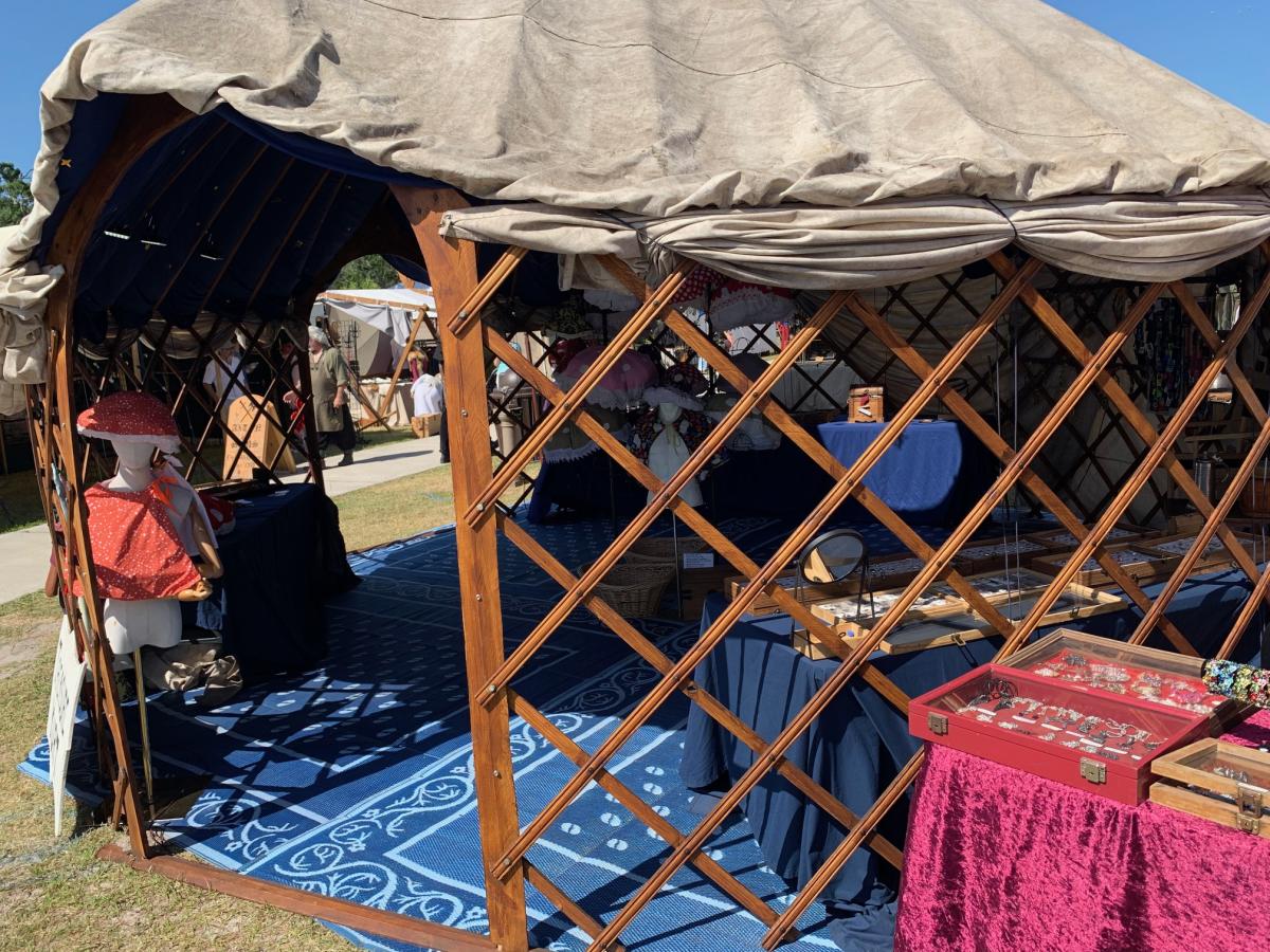 Sunny open side of the Treasure Yurt: wooden lattice, jewelry cases, magenta velvet, and a mushroom hat mannequin.